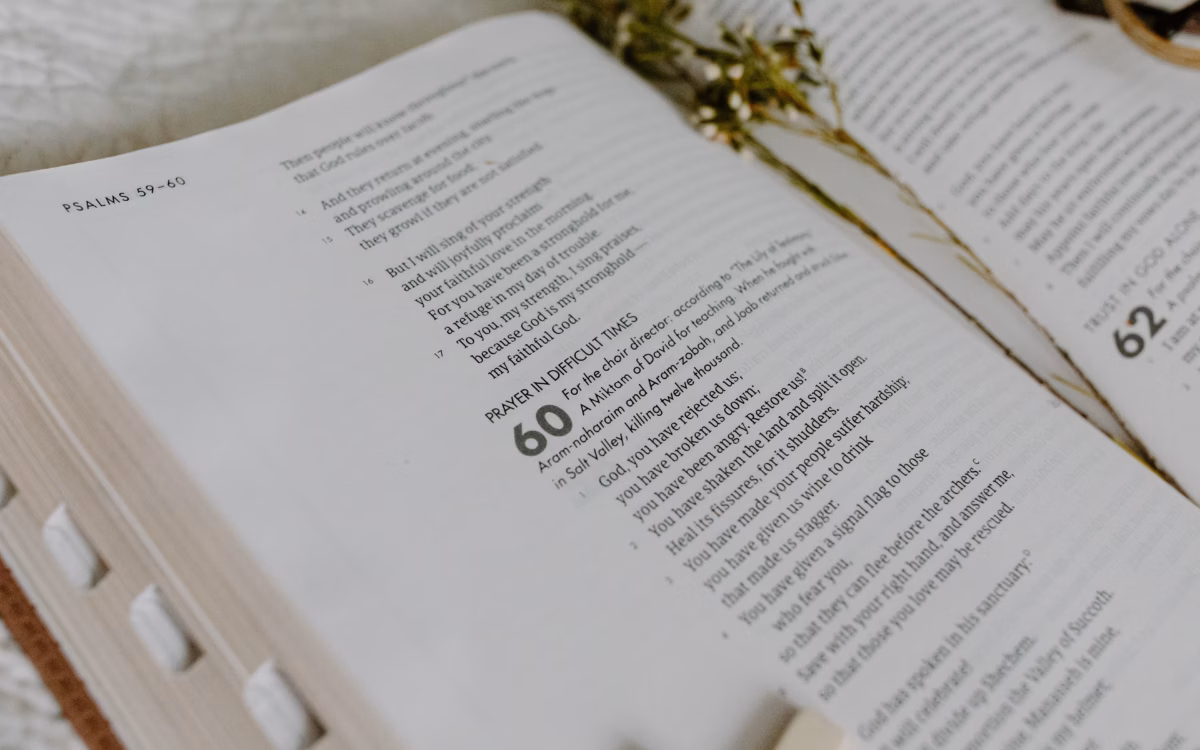 Open Bible on a wooden table with a hand resting across the pages — define covenant in the bible